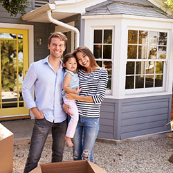 couple with a child standing in front of their new home